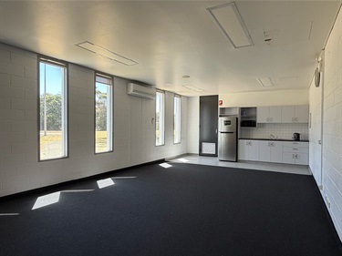 Room with carpet, kitchen bench, sink and fridge