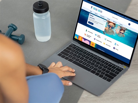 images of a person sitting on the floor in a gym looking at the new website on a laptop