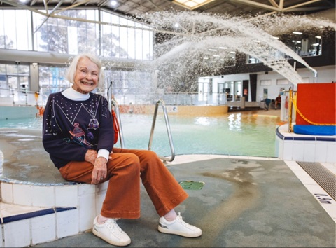 Lady sitting down next to Waves swimming pool smiling