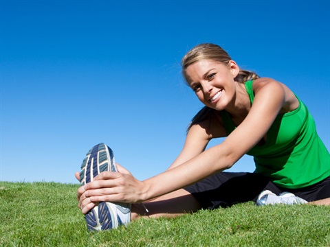 person stretching on grass whilst looking at the camera